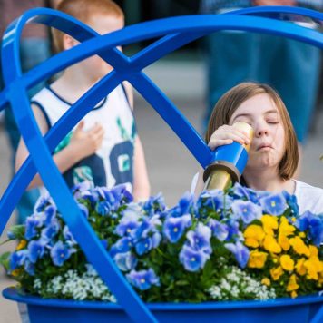Minnesota Arboretum_44 RobertEvansImagery.com RES04509 A child peers into a telescope for a close up of the brightly colored flowers at the Minnesota Arboretum.